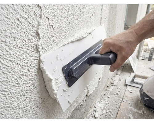 Handwerker trägt mit einer Glättkelle Putz auf eine Wand auf.