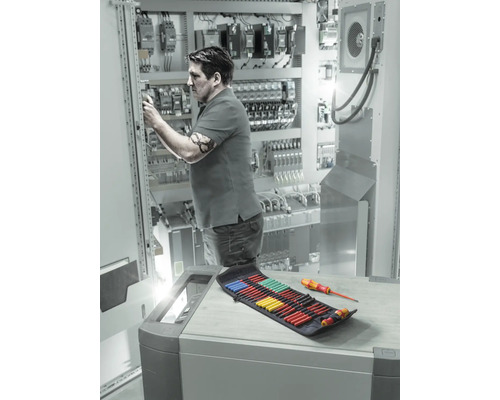 Elektriker arbeitet an Schaltschrank mit Schraubendreher-Set in der Nähe