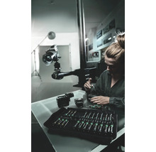 Frau repariert Kamera mit Schraubendreher-Set in Werkstatt