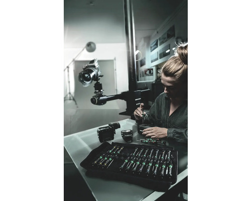 Frau repariert Kamera mit Schraubendreher-Set in Werkstatt