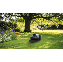 Szene mit Rasenmähroboter im Garten, Person in der Hängematte