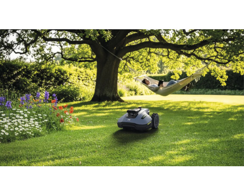Szene mit Rasenmähroboter im Garten, Person in der Hängematte