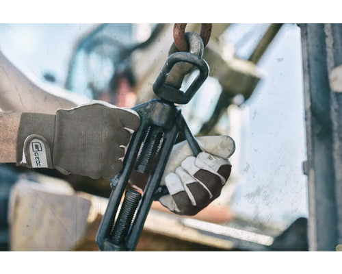 Nahaufnahme von Händen mit Arbeitshandschuhen, die einen Schraubstock bedienen