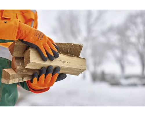 Person mit Arbeitshandschuhen, die Holzscheite trägt