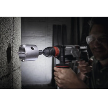 Ein Mann bohrt mit einer Mauerkrone ein Loch in eine Betonwand.