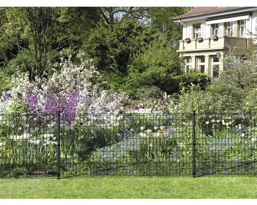 Gartenansicht mit Metallzaun zur Grundstückseingrenzung und Blumenbeeten im Hintergrund.