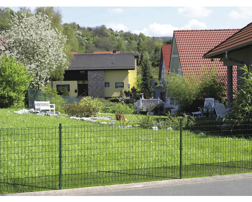 Ein grüner Doppelstabmattenzaun umfriedet ein Grundstück mit Häusern und Gärten.