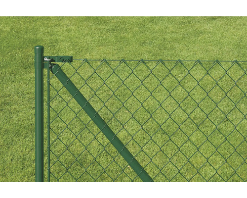 Detailansicht eines Maschendrahtzauns mit Zaunpfosten vor Rasenfläche