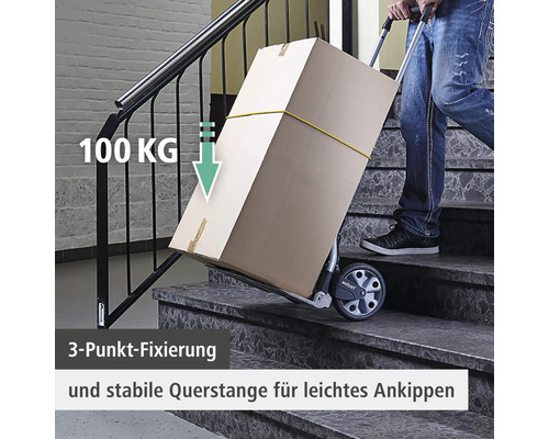 Eine Person transportiert eine Karton auf einem Treppensteiger mit einer Traglast von 100 Kilogramm auf einer Treppe.