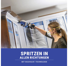 Frau sprüht mit einer Farbspritzpistole Farbe auf einen Schrank.