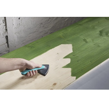 Ein Holzbrett wird mit einem Anstreicherwerkzeug gestrichen.