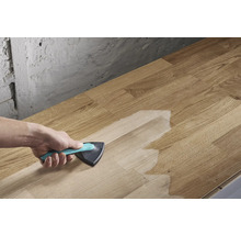 Eine Person trägt Oberflächenbehandlung mit einem Dreieckspinsel auf eine Holzplatte auf.