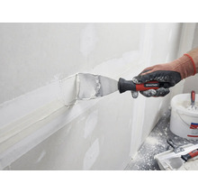 Eine Person spachtelt eine Wand mit einer Spachtelmasse und einem Spachtel von Rautner.