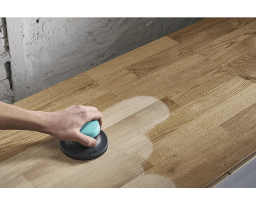 Eine Person schleift eine Holzplatte mit einem Exzenterschleifer.