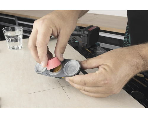 Mann setzt Schleifaufsatz in ein Farbnäpfchen ein.