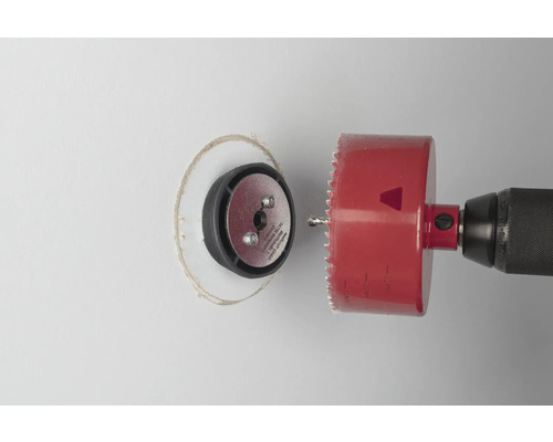 Bohrmaschine mit Lochsäge schneidet ein Loch in eine Wand