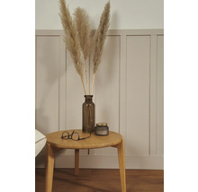 Dekoratives Arrangement mit Pampasgras in einer Vase, einer Kerze und einer Brille auf einem Holztisch