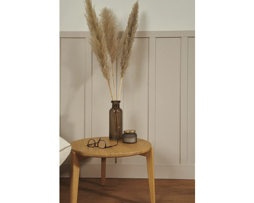 Dekoratives Arrangement mit Pampasgras in einer Vase, einer Kerze und einer Brille auf einem Holztisch