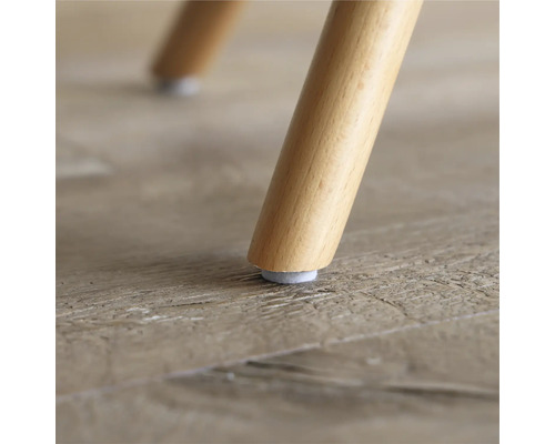 Nahaufnahme eines Stuhlbeins aus Holz mit Filzgleiter auf einem Holzboden