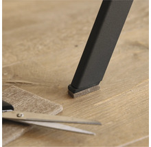 Filzgleiter an einem Stuhlbein mit Schere und Filzstück auf dem Boden