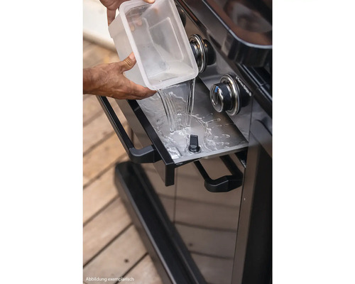 Wasser wird in die Fettauffangschale eines Grills gegossen.