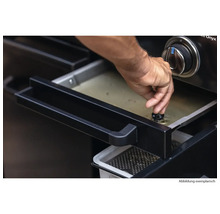 Eine Person reguliert die Fettablauf-Funktion eines Grills.