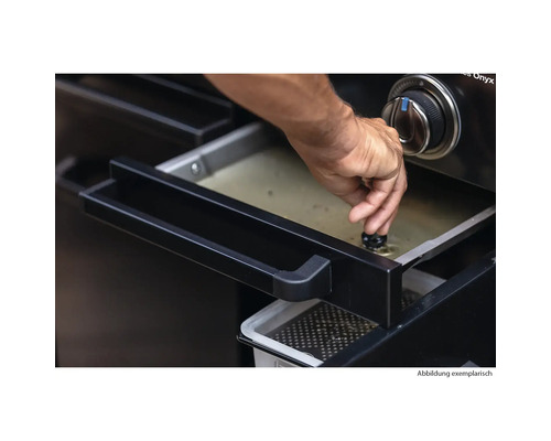 Eine Person reguliert die Fettablauf-Funktion eines Grills.