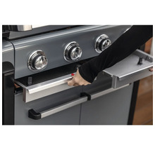 Detailansicht eines Gasgrills mit einer Person, die eine Schublade öffnet
