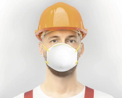 Ein Mann mit Schutzhelm und Atemschutzmaske.