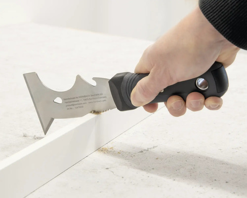 Eine Person verwendet einen Multifunktionsschaber zum Entfernen von Material von einer Oberfläche.