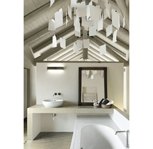 Badezimmer mit Waschbecken, Spiegel, Badewanne und dekorativer Beleuchtung unter einer Dachschräge