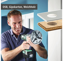 Mann bohrt mit einem Lochschneider ein Loch in eine OSB Platte, eine Gipskartonplatte und Weichholz