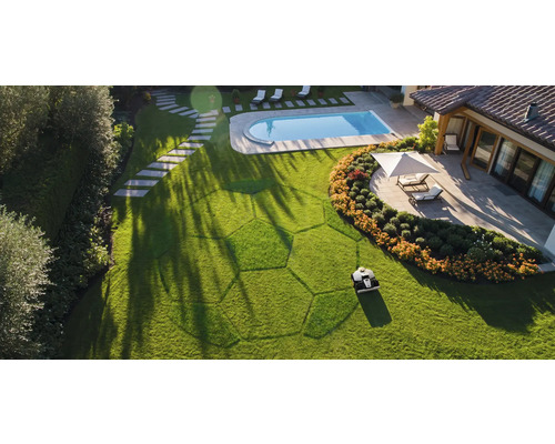 Ansicht von oben: Rasenroboter beim Rasenmähen in einem Garten mit Pool und Terrasse.