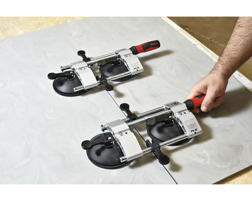 Zwei Fliesenheber mit Vakuumsaugern auf einer Fliese