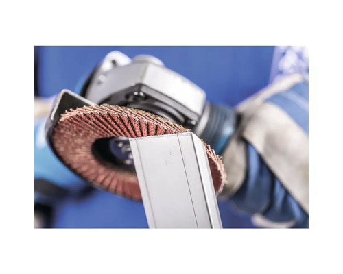 Ein Mann benutzt eine Schleifscheibe an einem Metallstück.