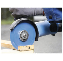 Eine Person sägt mit einem Winkelschleifer ein Holzbrett.