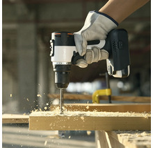 Eine Person bohrt mit einem Akku-Bohrschrauber ein Loch in ein Holzbrett.