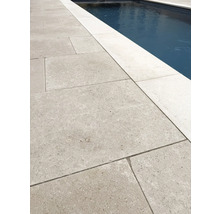 Großformatige Terrassenplatten aus Naturstein neben einem Swimmingpool, strukturierte Oberfläche, helle Poolumrandung.