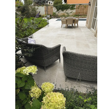 Helle Terrasse mit Steinplatten im Großformat, Geflecht-Lounge-Sesseln, Sitzgruppe und Garten mit Pflanzen. Organisiert gestaltet.