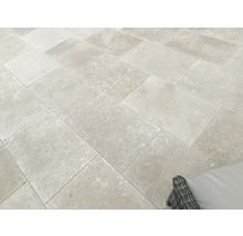 Terrassenplatten aus Feinsteinzeug in Natursteinoptik, verlegt im Versatz auf einer hellen und großzügigen Terrasse.