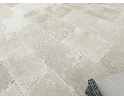 Terrassenplatten aus Feinsteinzeug in Natursteinoptik, verlegt im Versatz auf einer hellen und großzügigen Terrasse.