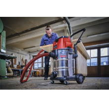 Werkstatt-Szene mit einem Einhell Nass-Trockensauger und einem Mann, der ein Holzbrett bearbeitet