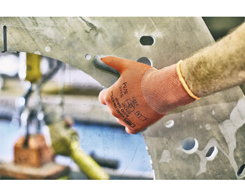 Eine Hand mit Arbeitshandschuh berührt ein Metallstück mit Löchern.