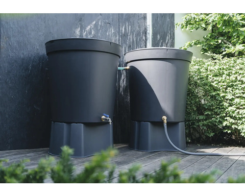 Zwei graue Regentonnen auf einer Holzterrasse mit Anschluss für einen Gartenschlauch und einem Wasserhahn.