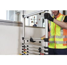 Ein Mann in Sicherheitsweste montiert ein modulares Gerüst.