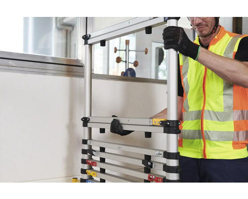 Ein Mann in Sicherheitsweste montiert ein modulares Gerüst.