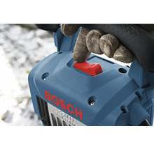 Hand mit Handschuh betätigt den roten Schalter einer blauen Bosch Stemmhammers.