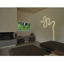 Modernes Wohnzimmer mit geschwungenem Lichtband an der Wand, Fernseher, Kamin und einer niedrigen Betonbank mit Brennholz.