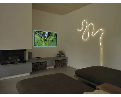 Modernes Wohnzimmer mit geschwungenem Lichtband an der Wand, Fernseher, Kamin und einer niedrigen Betonbank mit Brennholz.