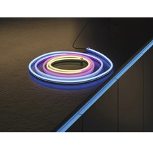 Flexibler LED-Neon-Strip, aufgerollt auf einer dunklen Fläche und als Akzentbeleuchtung an einer Möbelkante montiert.